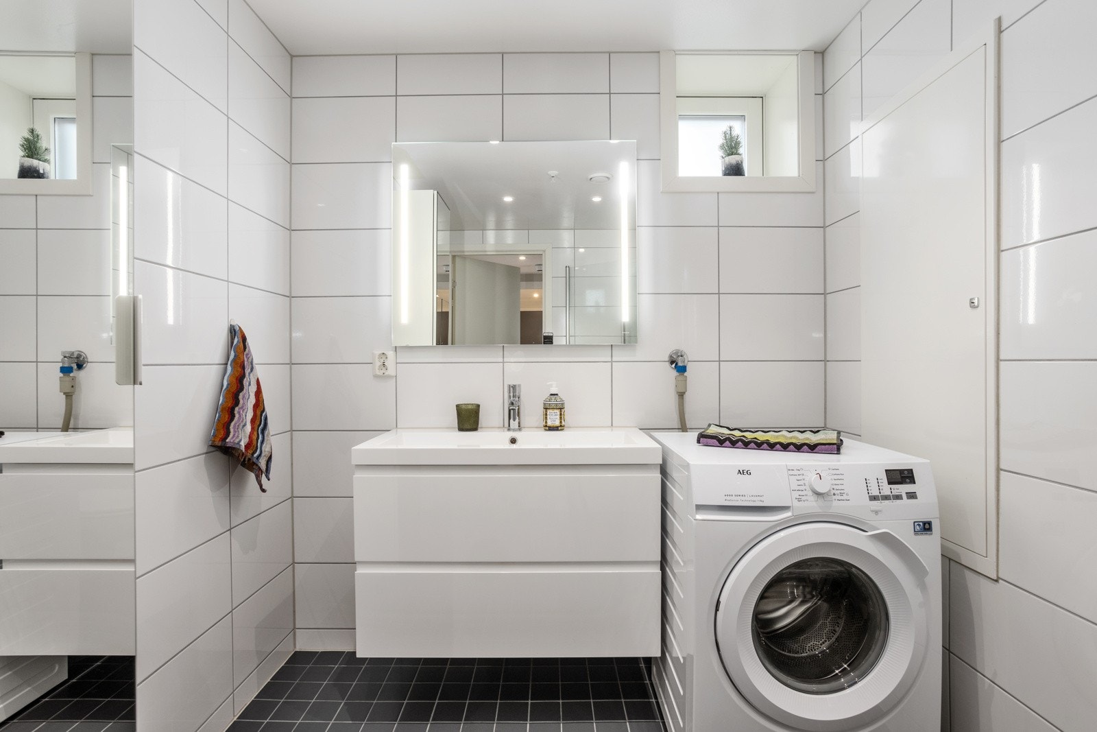 Speil over servant med integrert LED-belysning. Malt himling med innfelt downlights. Det er montert opplegg til vaskemaskin Galleribilde