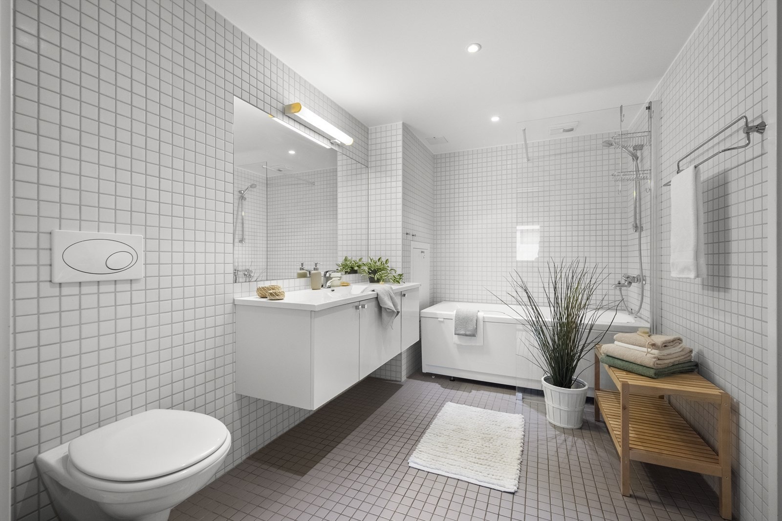 Badet er utstyrt med vegghengt toalett, servant nedfelt i innredning og badekar Galleribilde