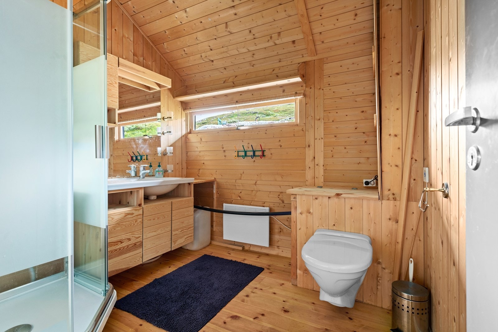 Badet er utstyrt med baderomsmøbel med Ålhytteinteriør med enkel servant, vegghengt Jets toalett og dusjkabinett. Galleribilde