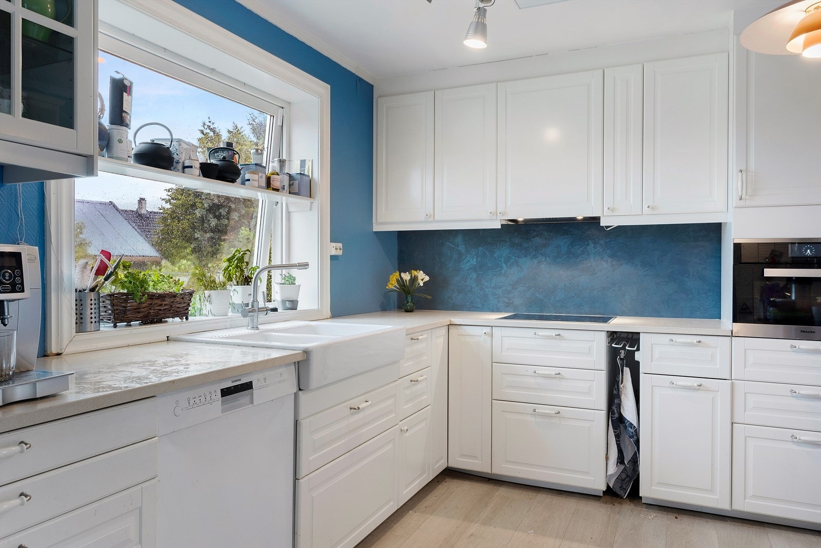 Kjøkkeninnredning fra Ikea med profilerte, hvitlakkerte fronter og tak høye skap. Integrert platetopp og stekeovn av fabrikasjonsmerke "Miele". Galleribilde
