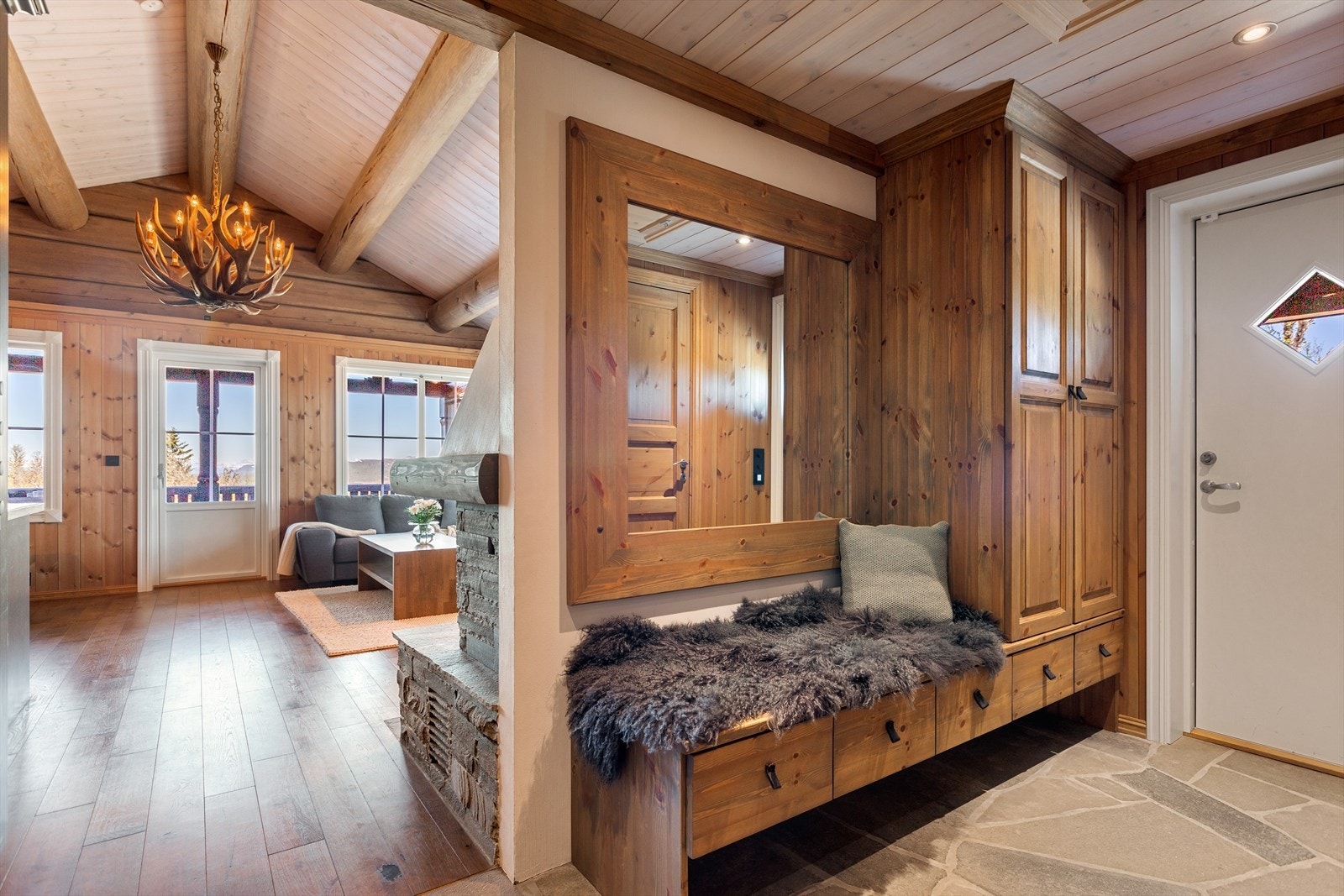 Fra det overbygde inngangspartiet med skiferheller, kommer en inn i entré med med plassbygd garderobeskap med sittebenk og skuffer i heltre. Galleribilde