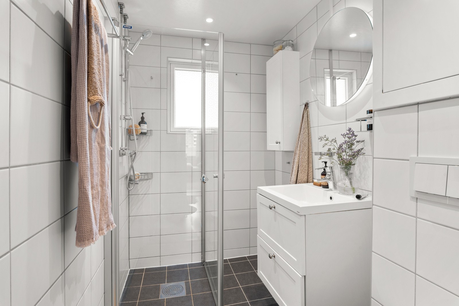 Videre har badet et vegghengt toalett, opplegg for vaskemaskin og et dusjhjørne med innfellbare glassdører. Galleribilde
