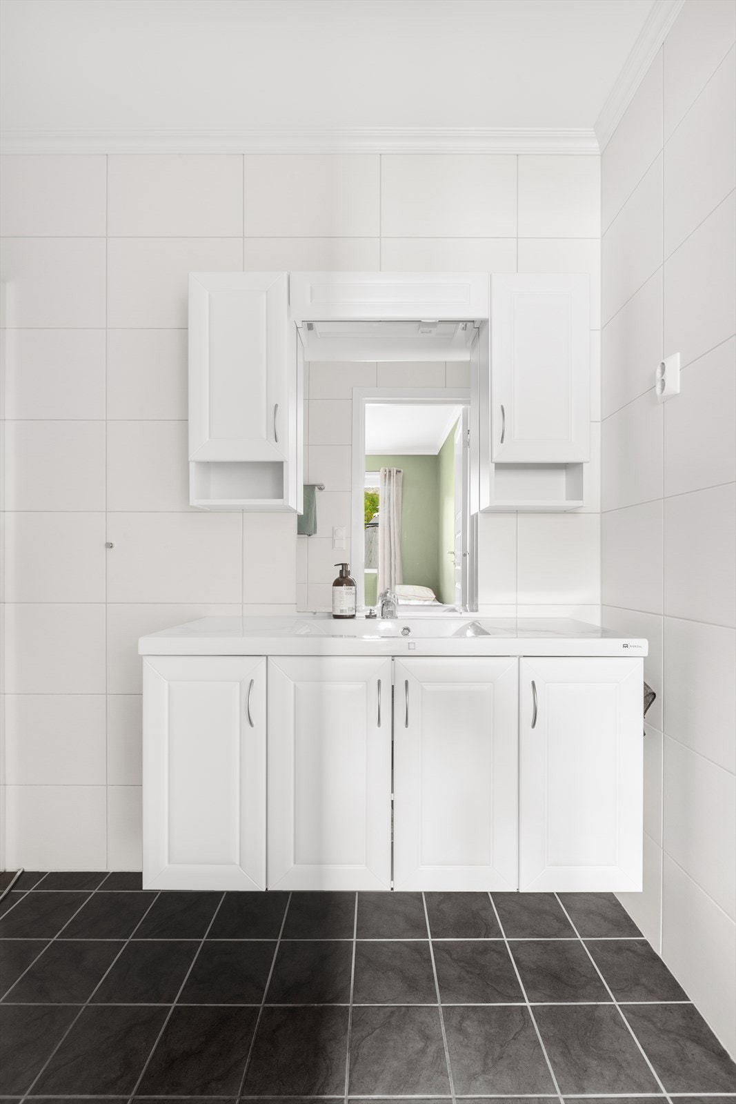 Baderommet er moderne og romslig med lyse fliser og stilrent interiør Galleribilde