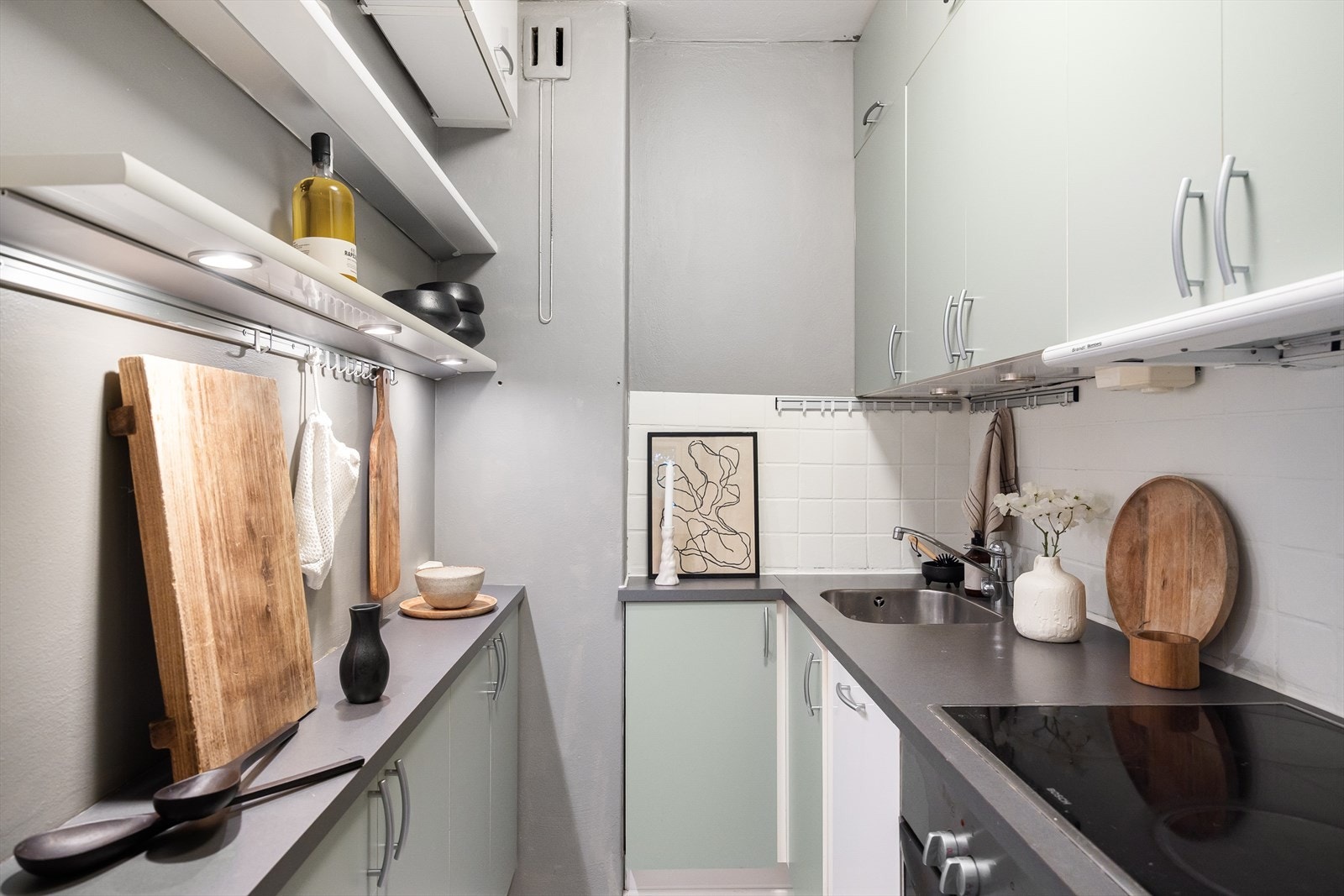 Skjermet, arealeffektivt kjøkken med masse lagringsplass i skap og vegghengte hyller Galleribilde