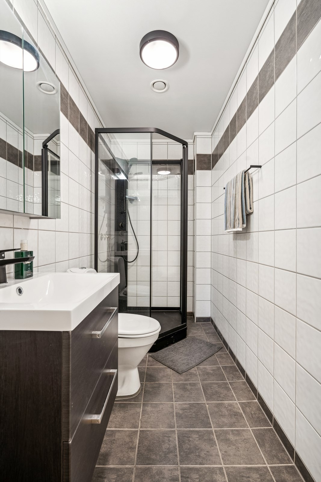 Badet er innredet med servantskap med ett-greps blandebatteri, speilskap, lysarmatur, gulvstående toalett og dusjkabinett. Galleribilde