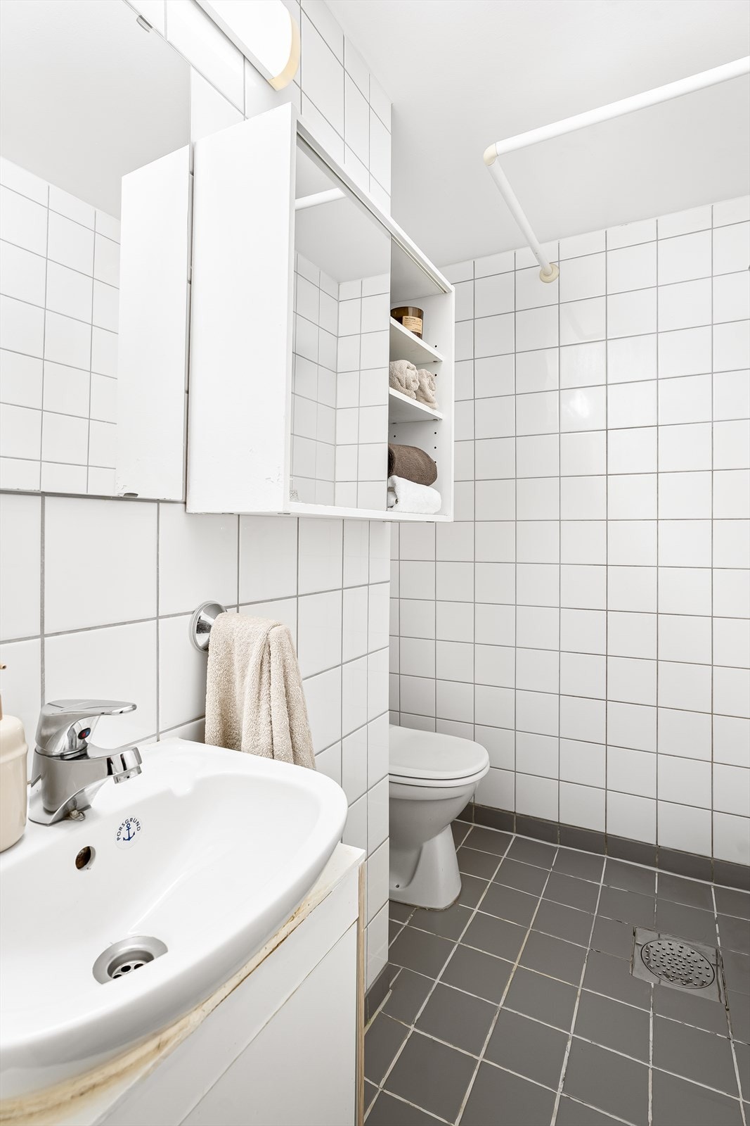 Badet er utstyrt med vegghengt/gulvstående servantskap med ett-greps armatur, gulvstående toalett og vegghengt speil med overbelysning. Galleribilde