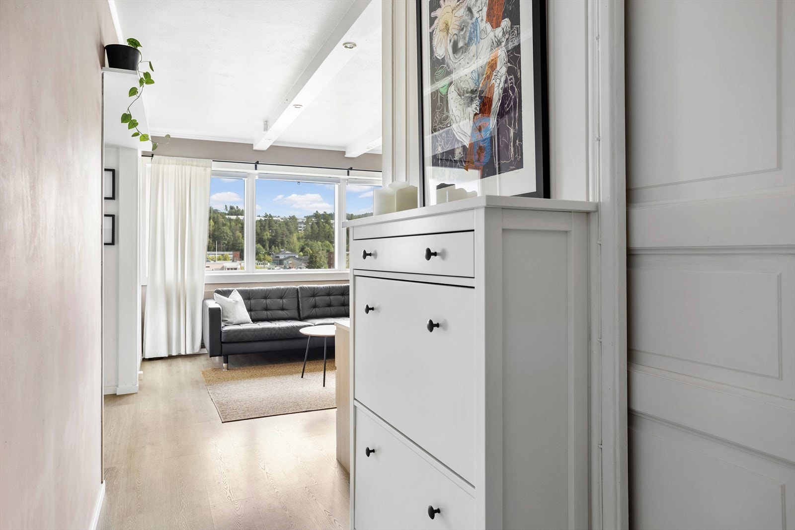 Entreen har laminat fra 2021 på gulv, en vegg med hvitmalt panel, samme pene fargetone som i stuen på øvrige vegger og downlights i himlingen. Galleribilde