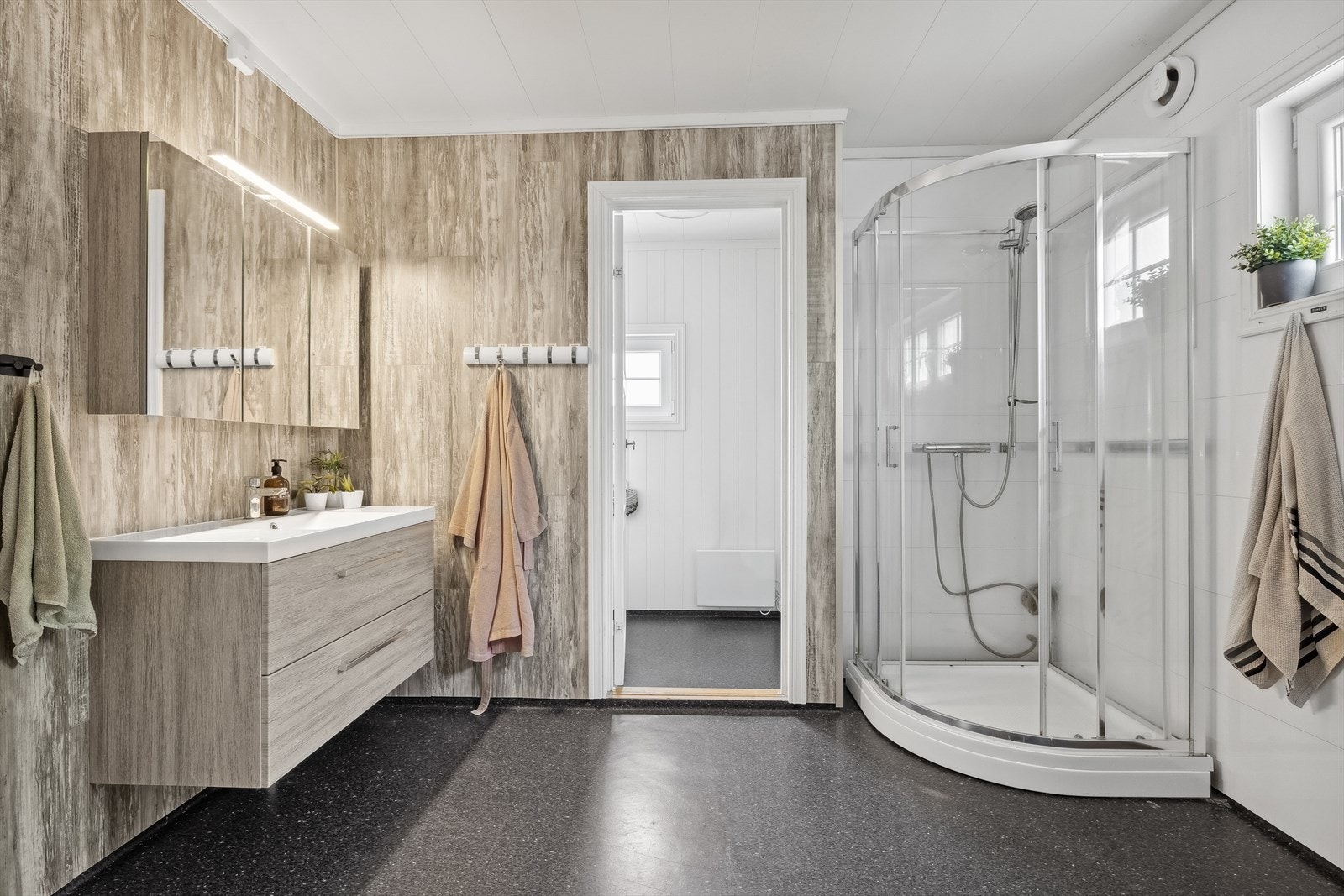 Badet er utstyrt med servant m/speil, dusjkabinett, toalett, badekar og opplegg til vaskemaskin og tørketrommel Galleribilde