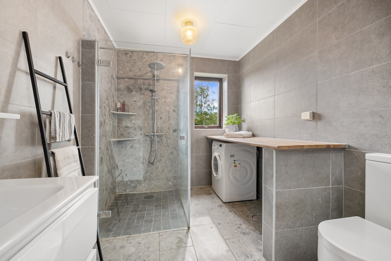 Badet er pusset opp i senere tid, og innehar moderne farger og fliser, med dusj, wc, servant og vaskemaskin med benk. Galleribilde