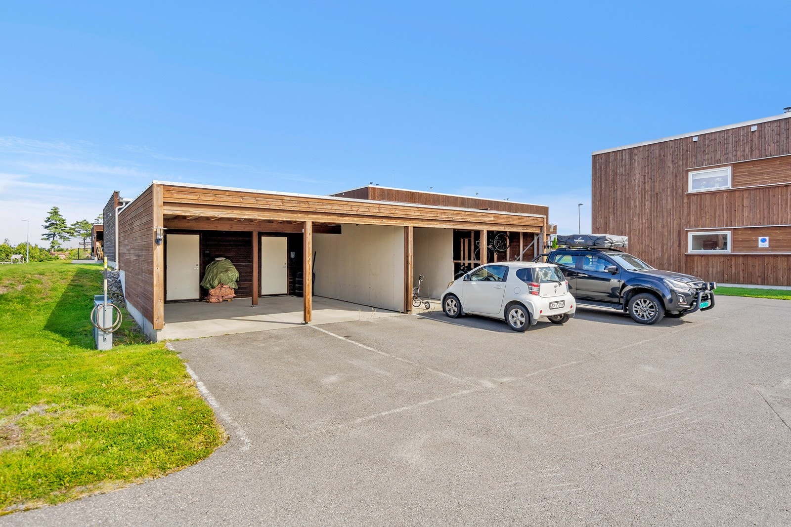 Carport helt til venstre følger leiligheten. Innerst i carporten er det sportsbod på 5 kvm. Det er også klargjort for elbillader. Galleribilde