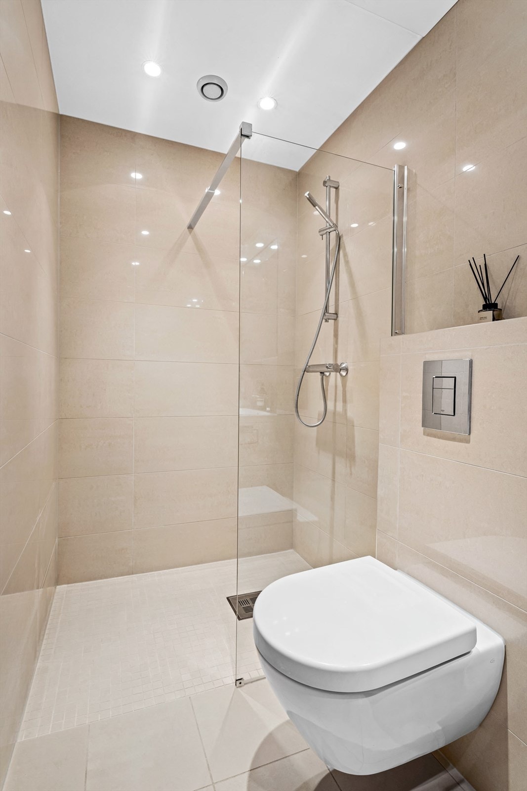 Stor dusjnisje med ny glassvegg i 2024 og vegghengt wc med innebygget sisterne. Galleribilde