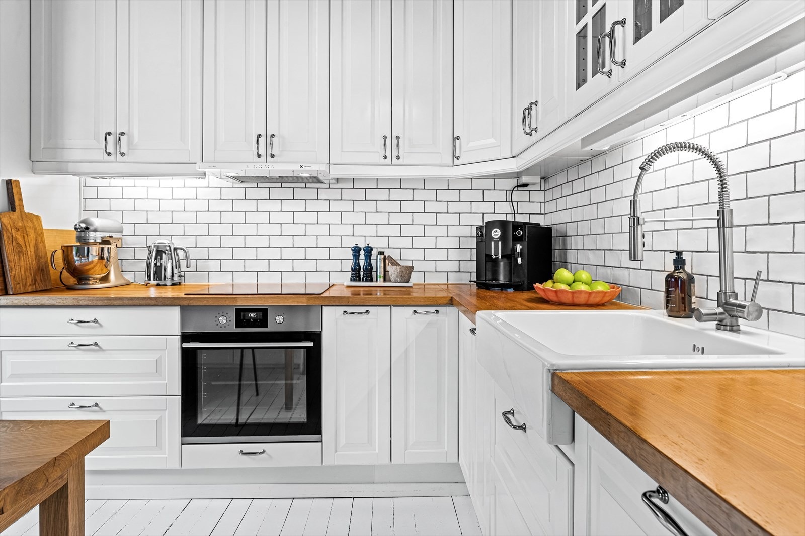 Pen, klassisk kjøkkeninnredning med profilerte fronter, stor kjøkkenvask, heltre benkeplate og integrerte hvitevarer. Galleribilde