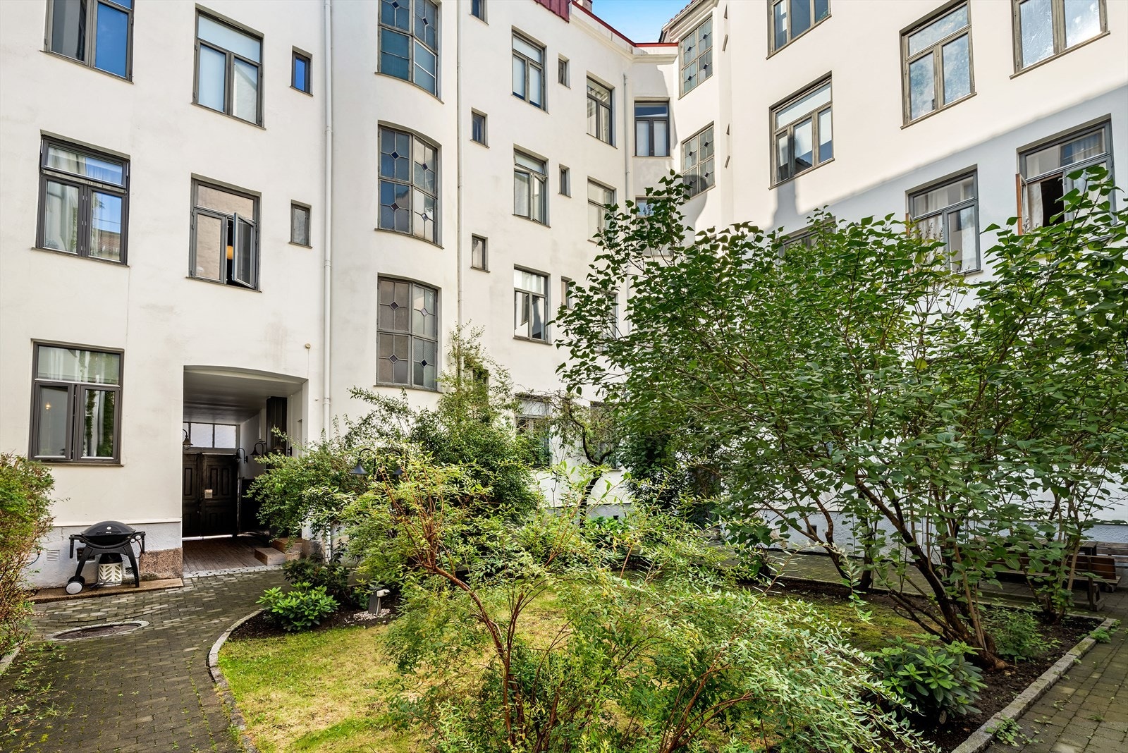 Pent opparbeidet bakgård med beplantning, sittegruppe og sykkelparkering. Galleribilde