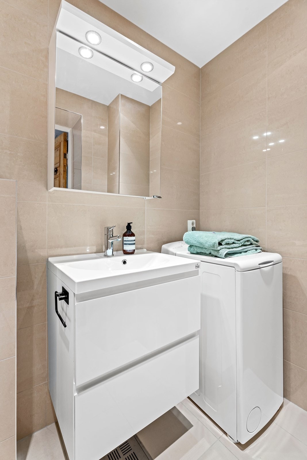 Servant med skuffer, speilskap med lys og opplegg for vaskemaskin. Galleribilde