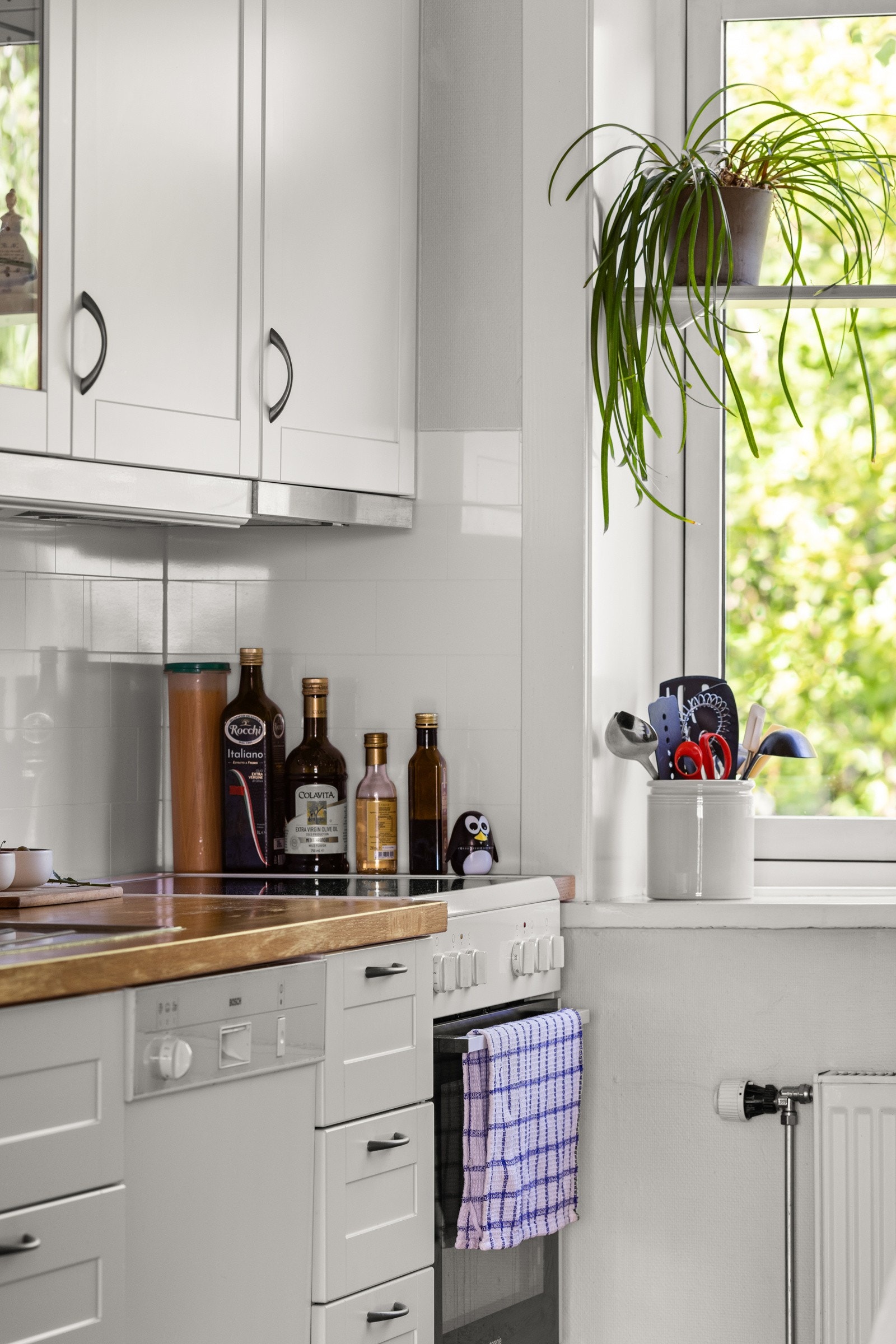 Kjøkkeninnredning med 1-speils og vitrineskap, plater på vegg over x-finer benkeplate med nedfelt vaskekum m/ bl.batteri. Galleribilde