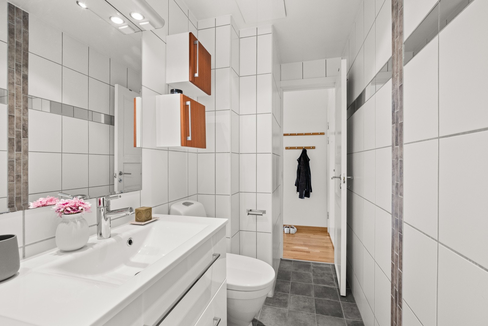 Badet har en vegghengt servantinnredning, speil med belysning, dusjhjørne med skyvedør, toalett, opplegg for vaskemaskin og gulvvarme. Galleribilde