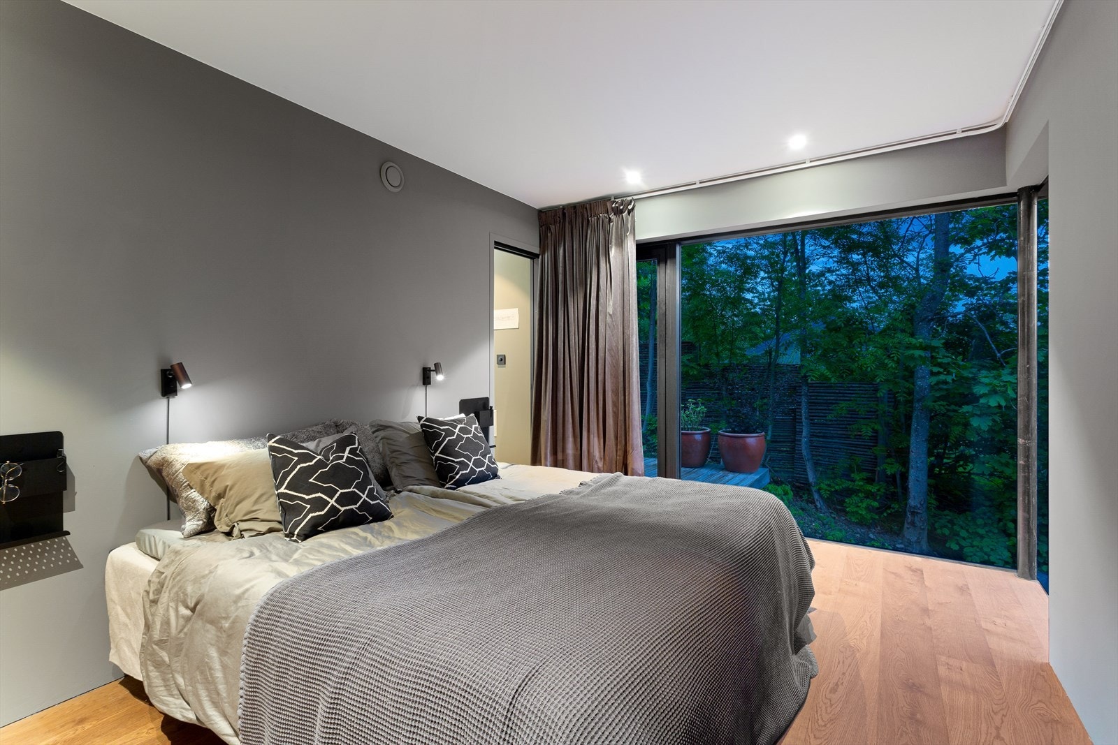 Det store glasshjørnet på soverommet gjør at man kan ligge i sengen og se rett ut på den grønne og frodige naturen utenfor. Galleribilde