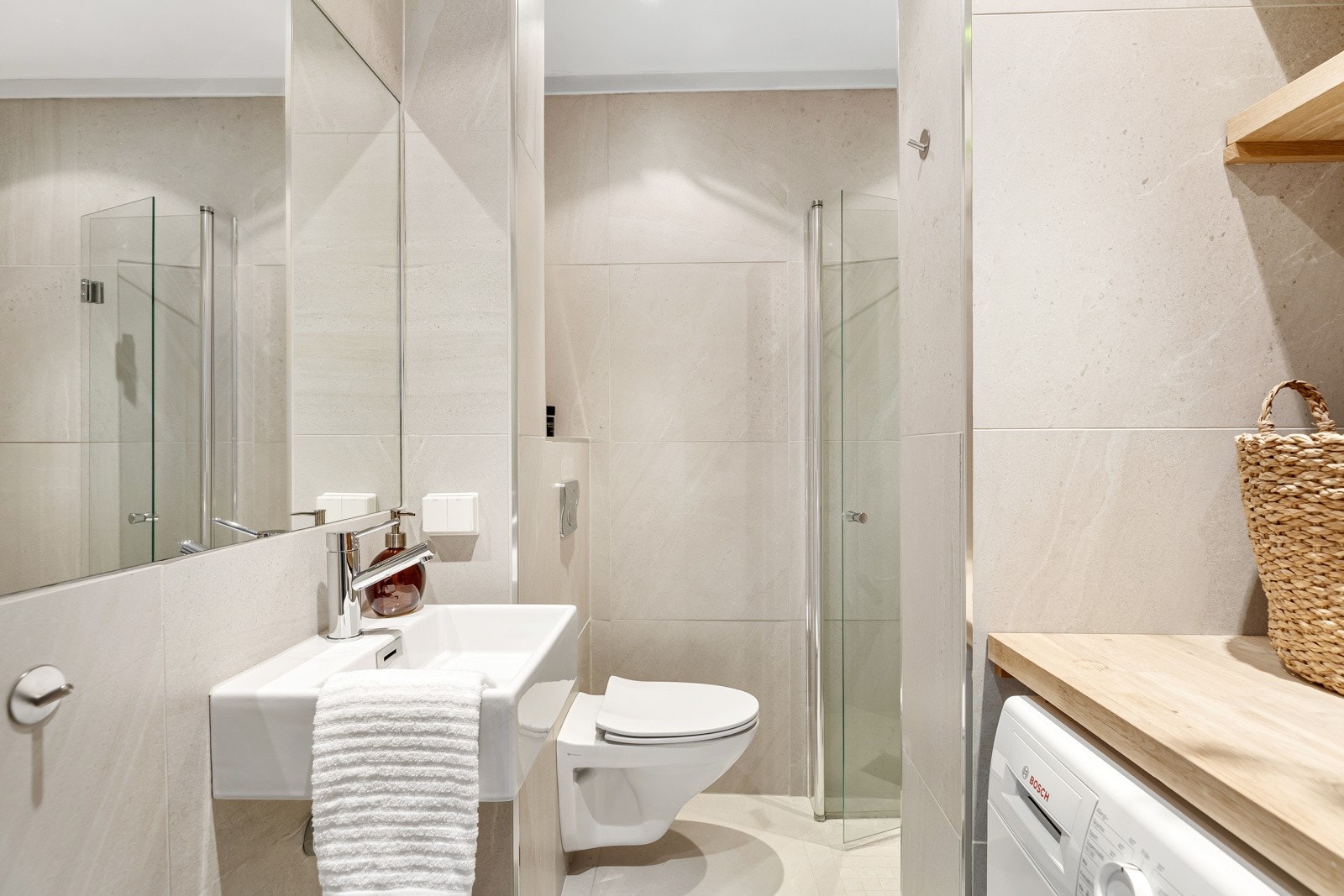 Flislagt bad med varmekabler, dusjnisje, veggmontert servantskap og toalett samt opplegg for vaskemaskin Galleribilde