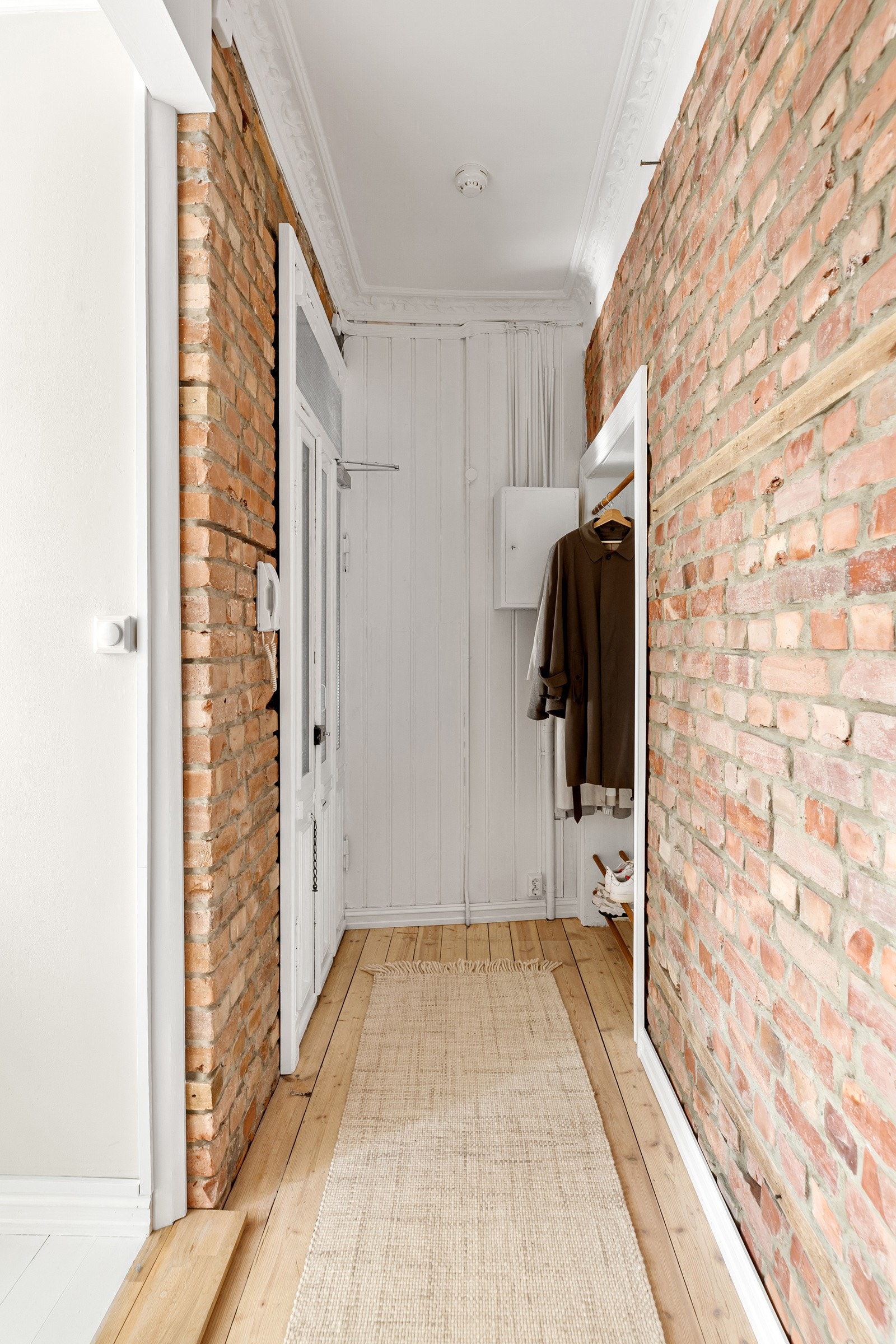 Innbydende entré med god plass til sko og yttertøy i nisje. Gjennomgående tregulv, synlig teglsteinsvegger samt malt panel gir et godt førsteinntrykk av boligen. Dørcalling. Galleribilde