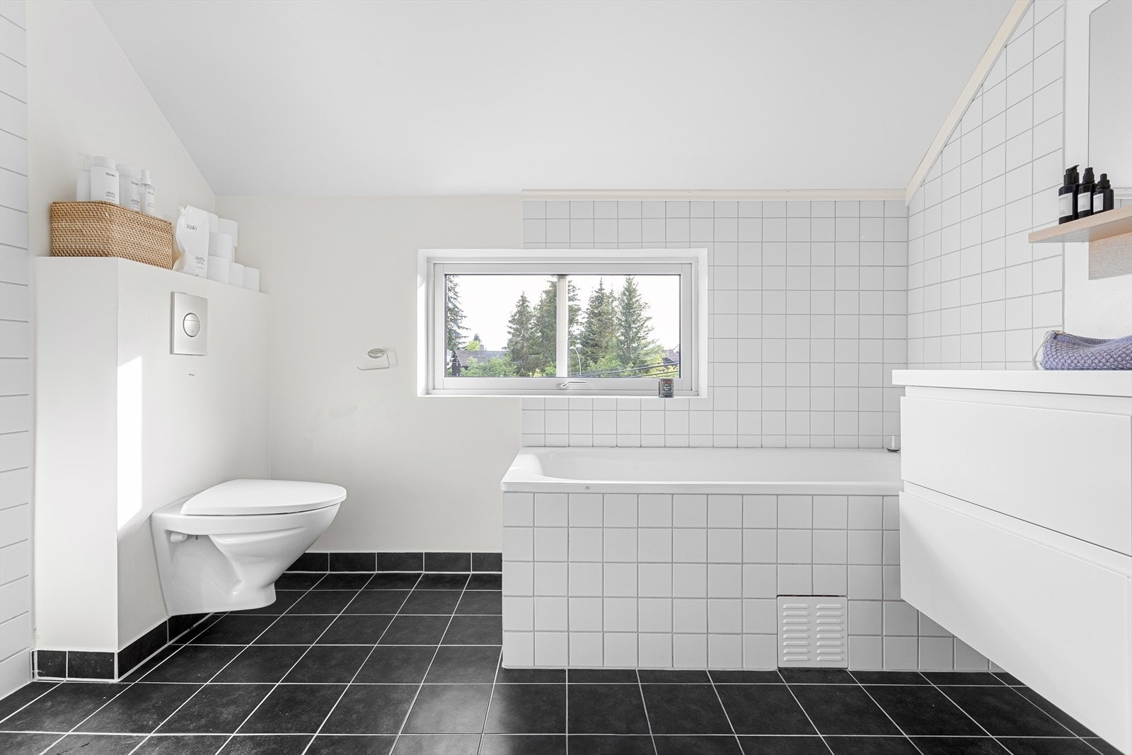 Romslig bad i 2. etasje. Badet inneholder frittstående badekar, dusjnisje med innfellbare glassdører, heldekkende servant med skuffer under og vegghengt toalettsisterne. Galleribilde