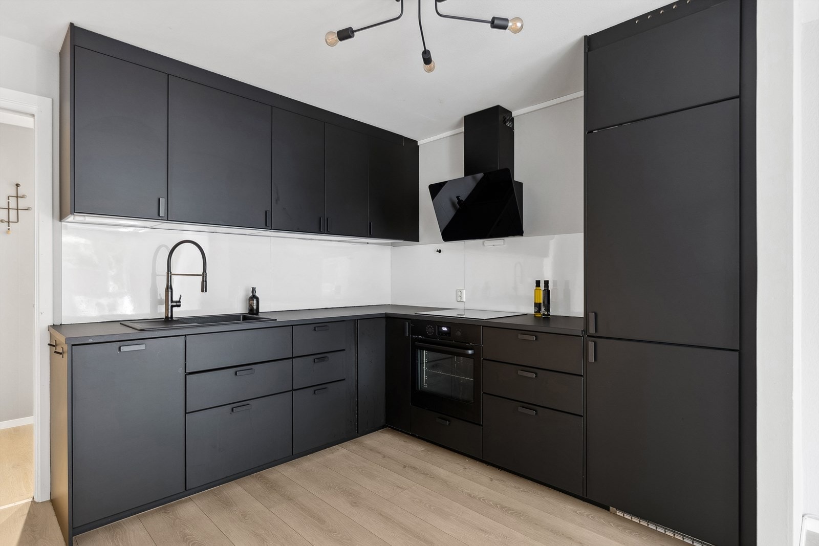 Stilrent kjøkken fra 2021 med glatt laminert kjøkkeninnredning, lys under overskap, plater mellom overskap og laminert benkeplate Galleribilde