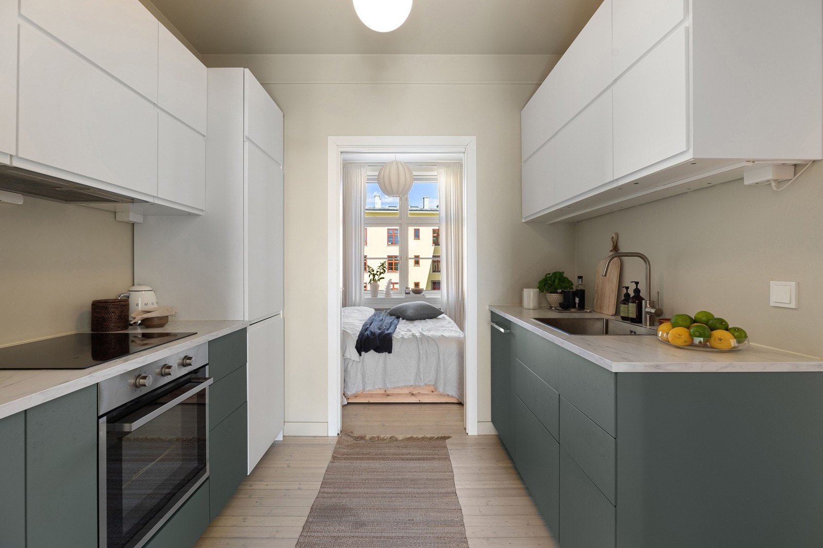 Slette fronter med lyse overskap. Fra overskapene er det benkebelysning som lyser opp benkeplaten som bryter fint mot de mørke underskapene/skuffene Galleribilde