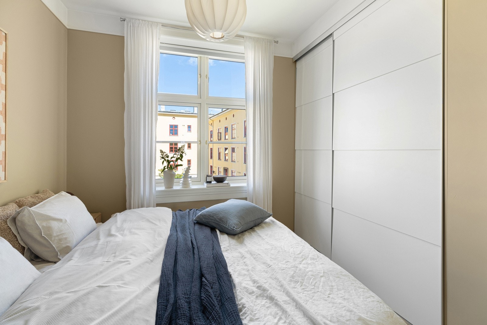 Soverommet er malt i en lun tone og vender ut mot frodig bakgård Galleribilde