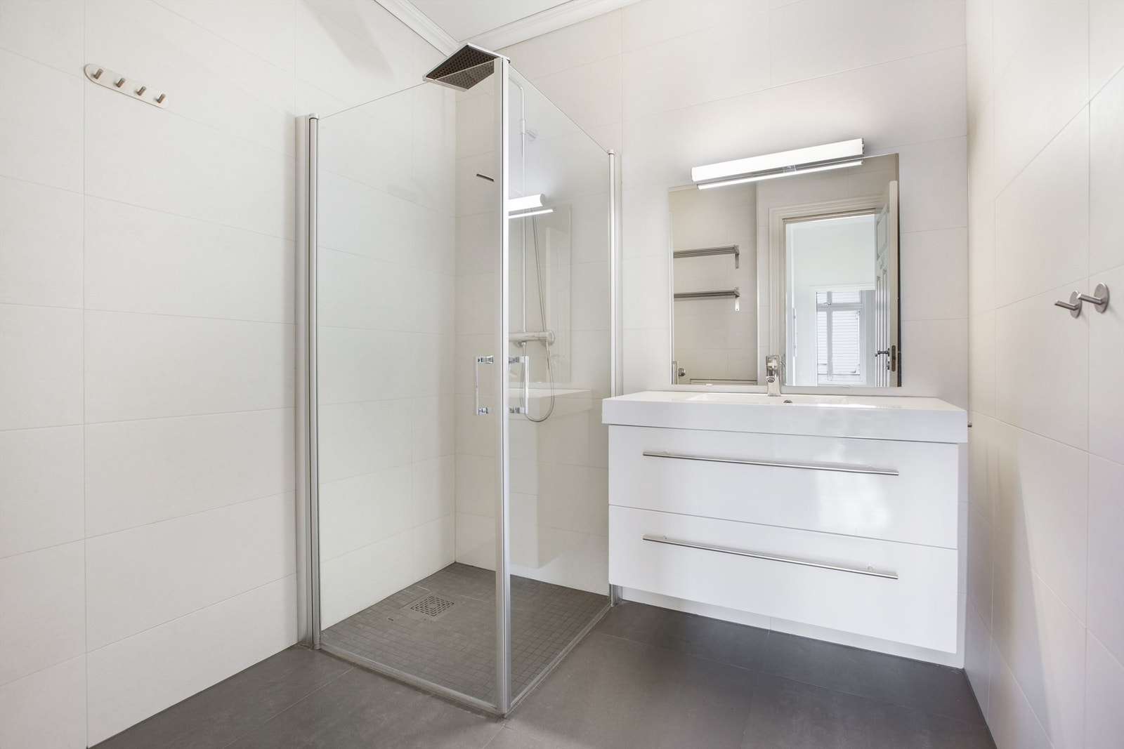 Badet har dusjhjørne med foldedører av glass og regnfallsdusj Galleribilde