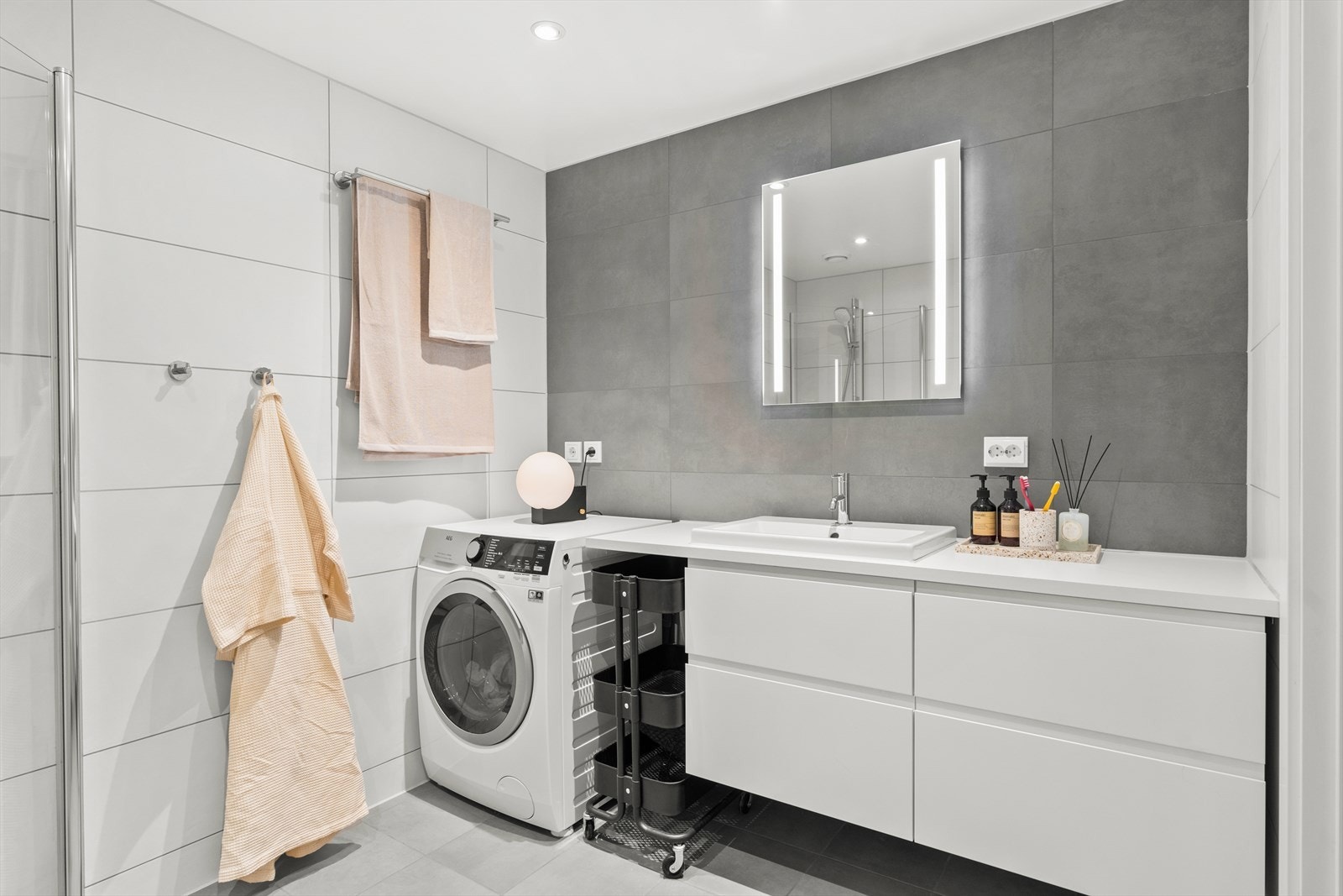 Badet er innredet med vegghengt klosett, servant nedfelt i innredning og dusjhjørne med svingbare glassdører. Det er opplegg for vaskemaskin og balansert ventilasjon. Galleribilde