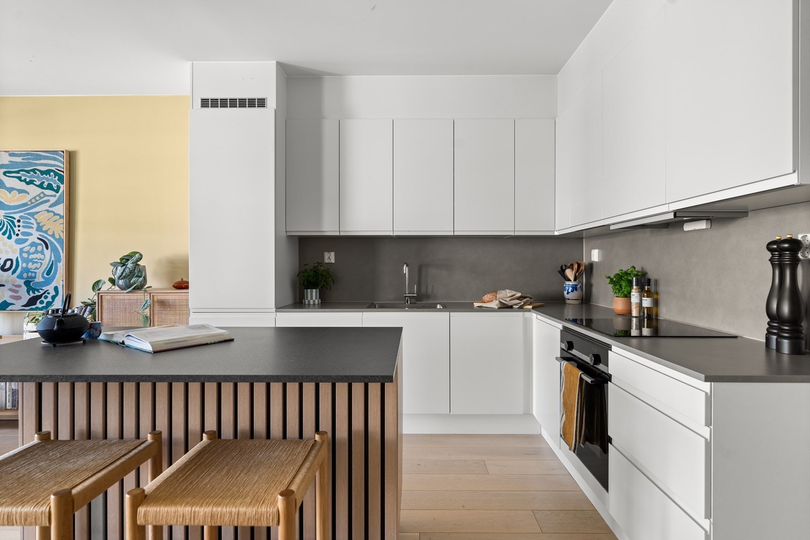 Pent kjøkken med en praktisk og delikat kjøkkenøy dekket i moderne spiler. Kjøkkenet er i åpen løsning mot stuen, noe som skaper en hyggelig og sosial atmosfære - her er det god skap- og benkeplass. Galleribilde