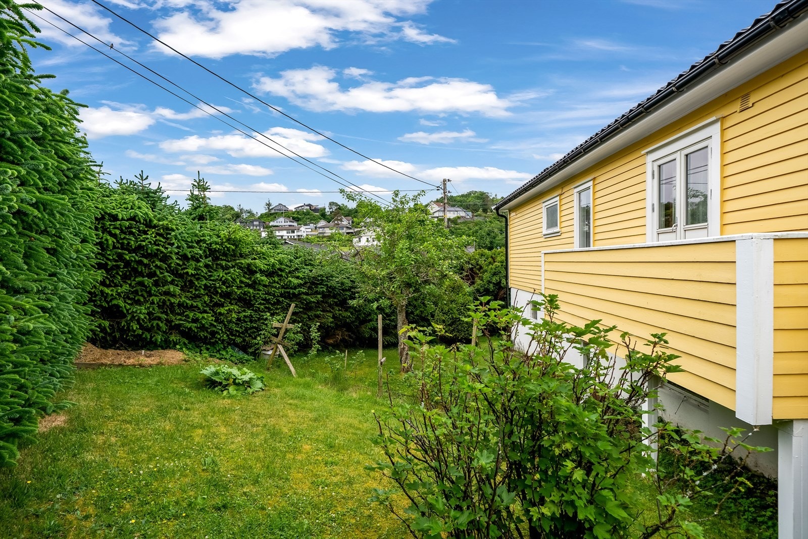 Usjenert hage på baksiden med potensiale til å lage til en trivelig uteplass. Galleribilde