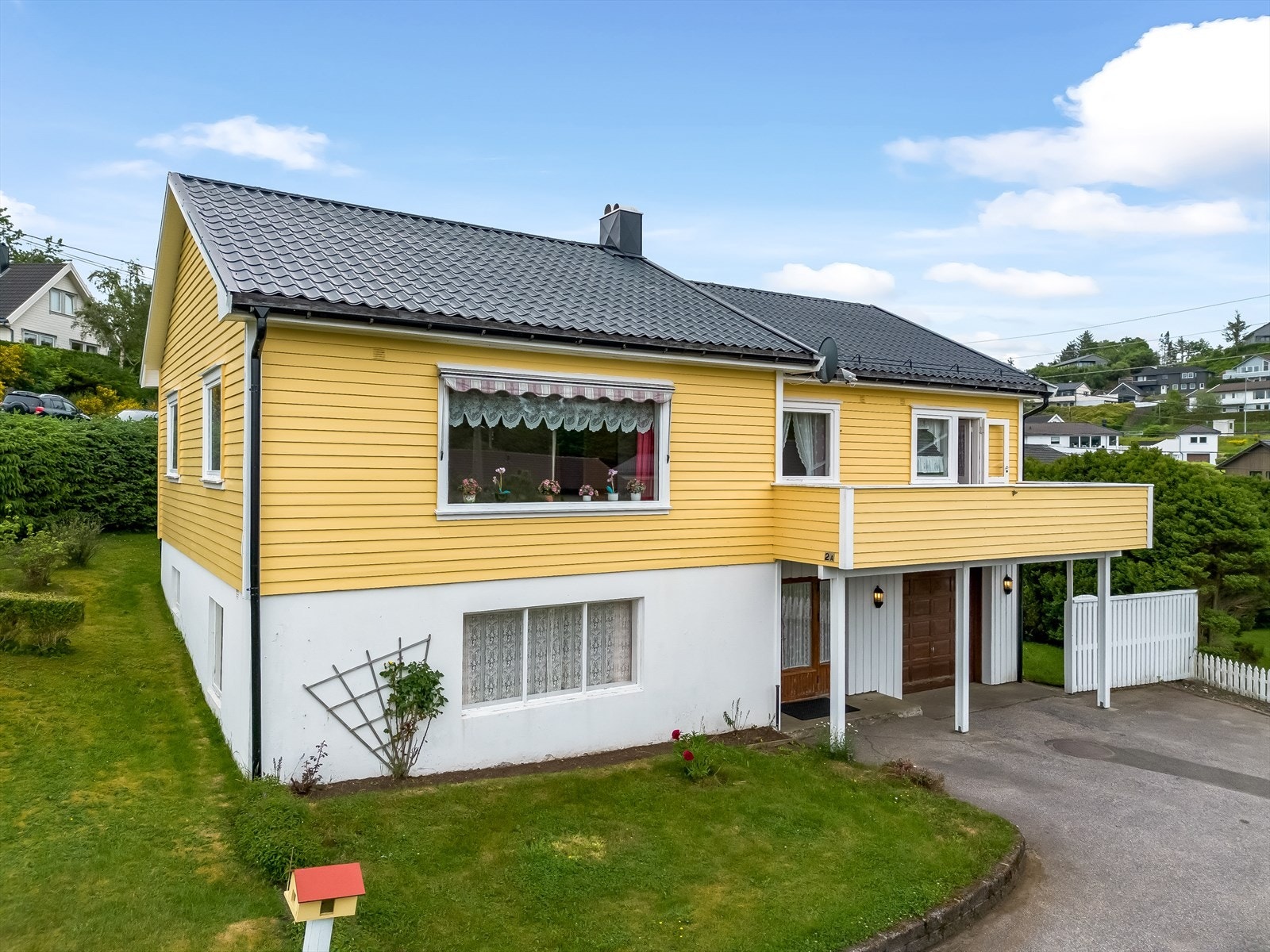 Tomta er pent opparbeidet med plenlagte områder, beplantning og asfaltert tun. Galleribilde