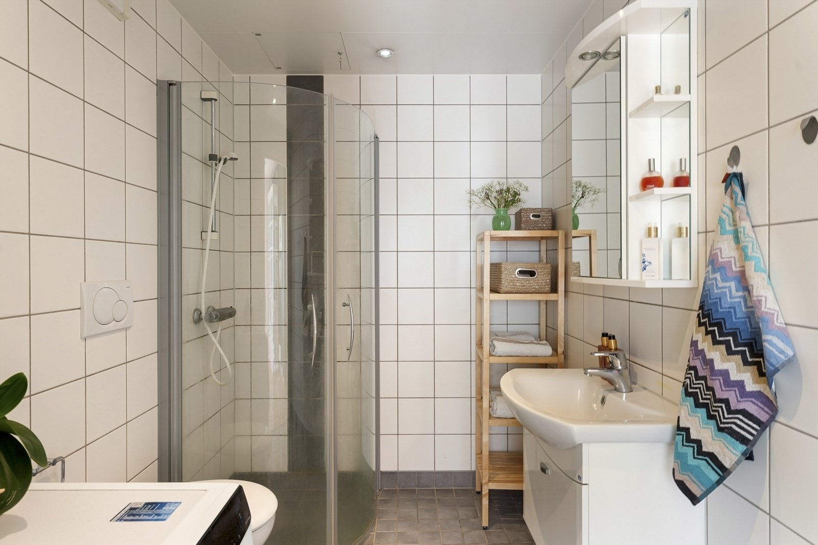Badet har en himling med lakkerte stålplater og innfelte downlights, samt flislagte vegger og gulv med elektrisk gulvvarme Galleribilde