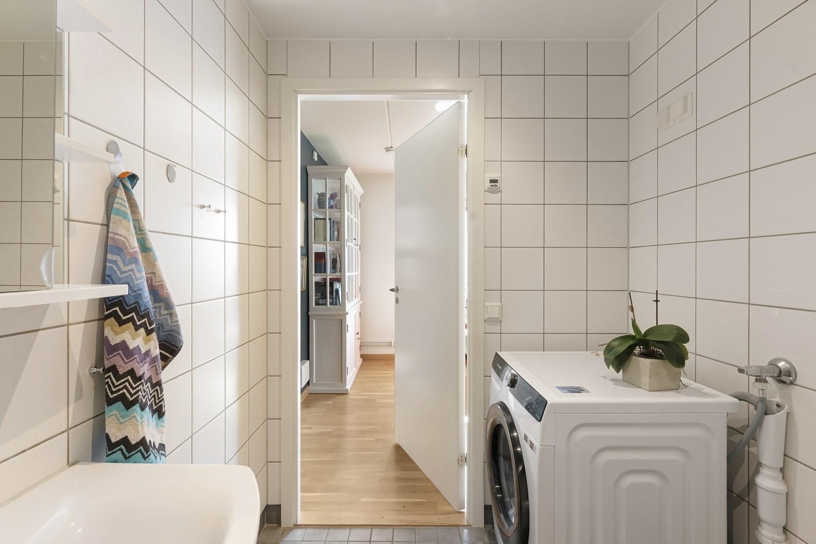 Innredningen består av en servant, et speilskap med lys, et vegghengt toalett og et dusjhjørne med svingbare glassdører. Det er også opplegg for vaskemaskin Galleribilde
