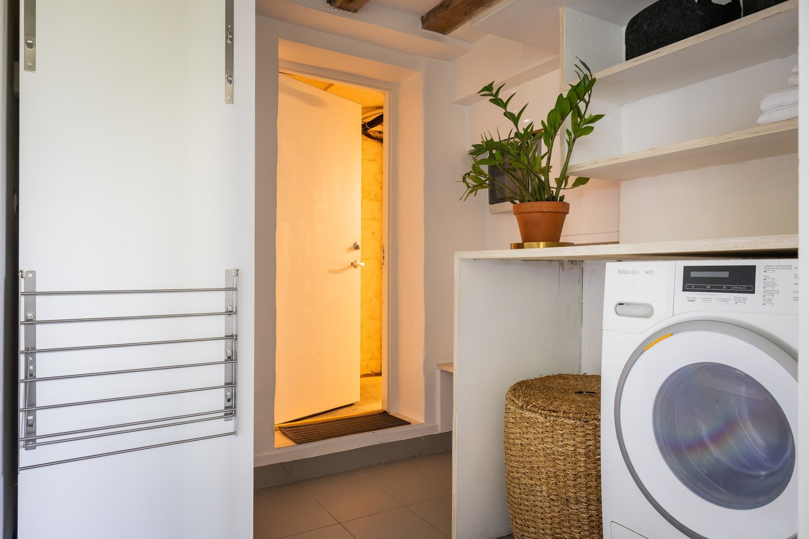 Vaskerom i kjeller med god plass til vaskemaskin og tørketrommel. Benk over vaskemaskin. Garderobeskap med glatte fronter. Åpne hyller på vegg over benk. Varmtvannsbereder plassert på vaskerom. Galleribilde