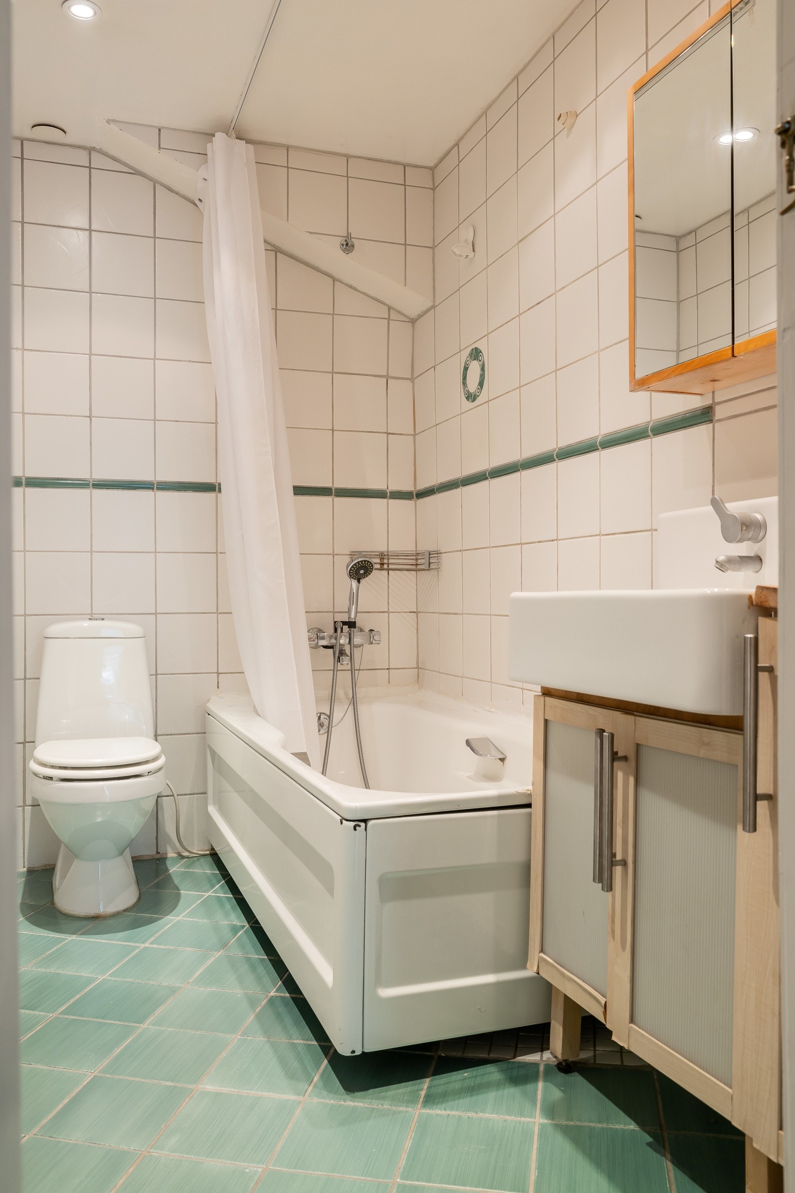 Bad i hybel i 1.etasje består av servantskap med glatte fronter og heldekkende servant. Speilskap på vegg over servant. Galleribilde