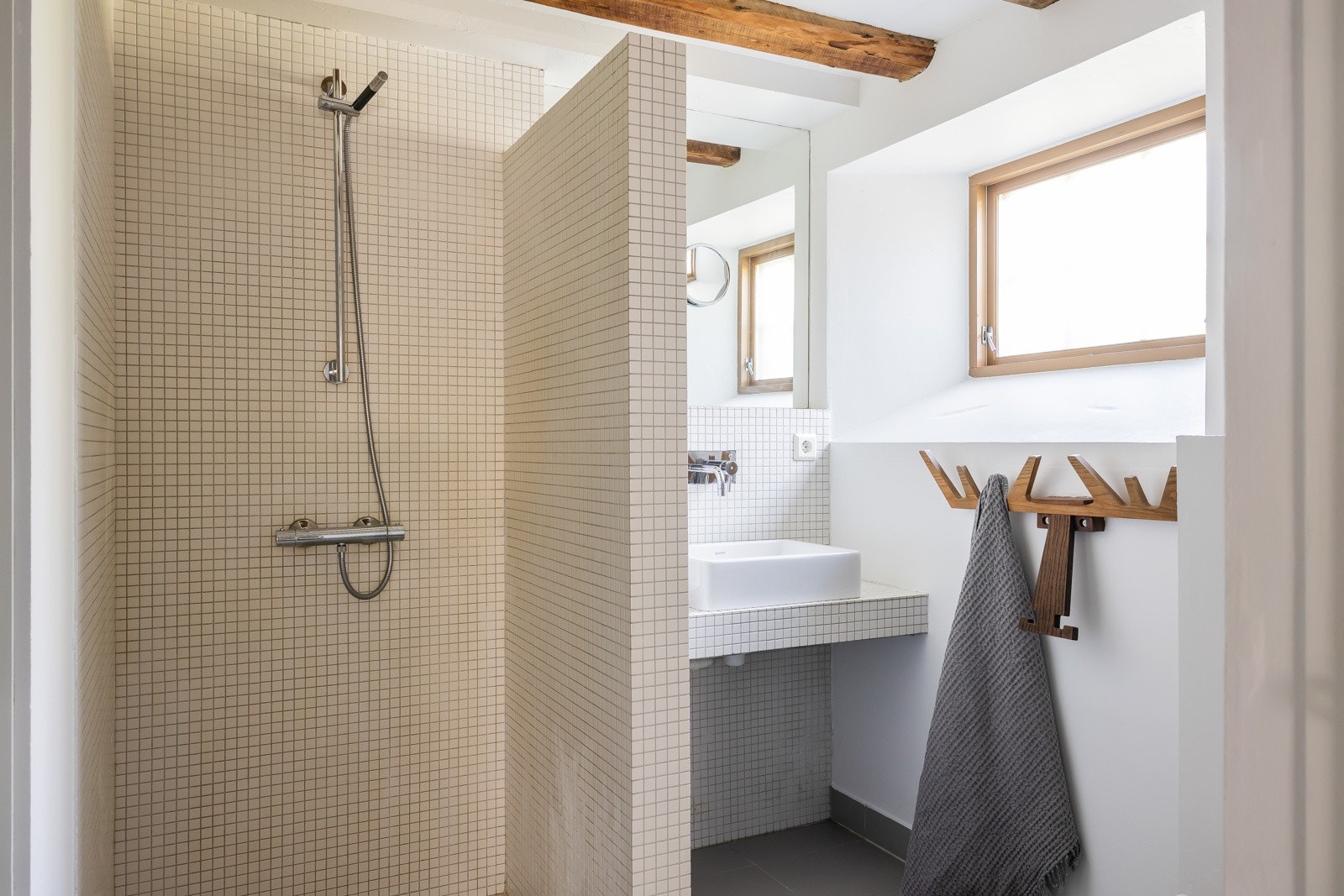 Badet inneholder servant bolle på flislagt plate/benk, speil på vegg over servant,veggmontert klosett. Det er nedsenket dusjsone med dusjutstyr, sluk og termostatstyrt blandebatteri Galleribilde