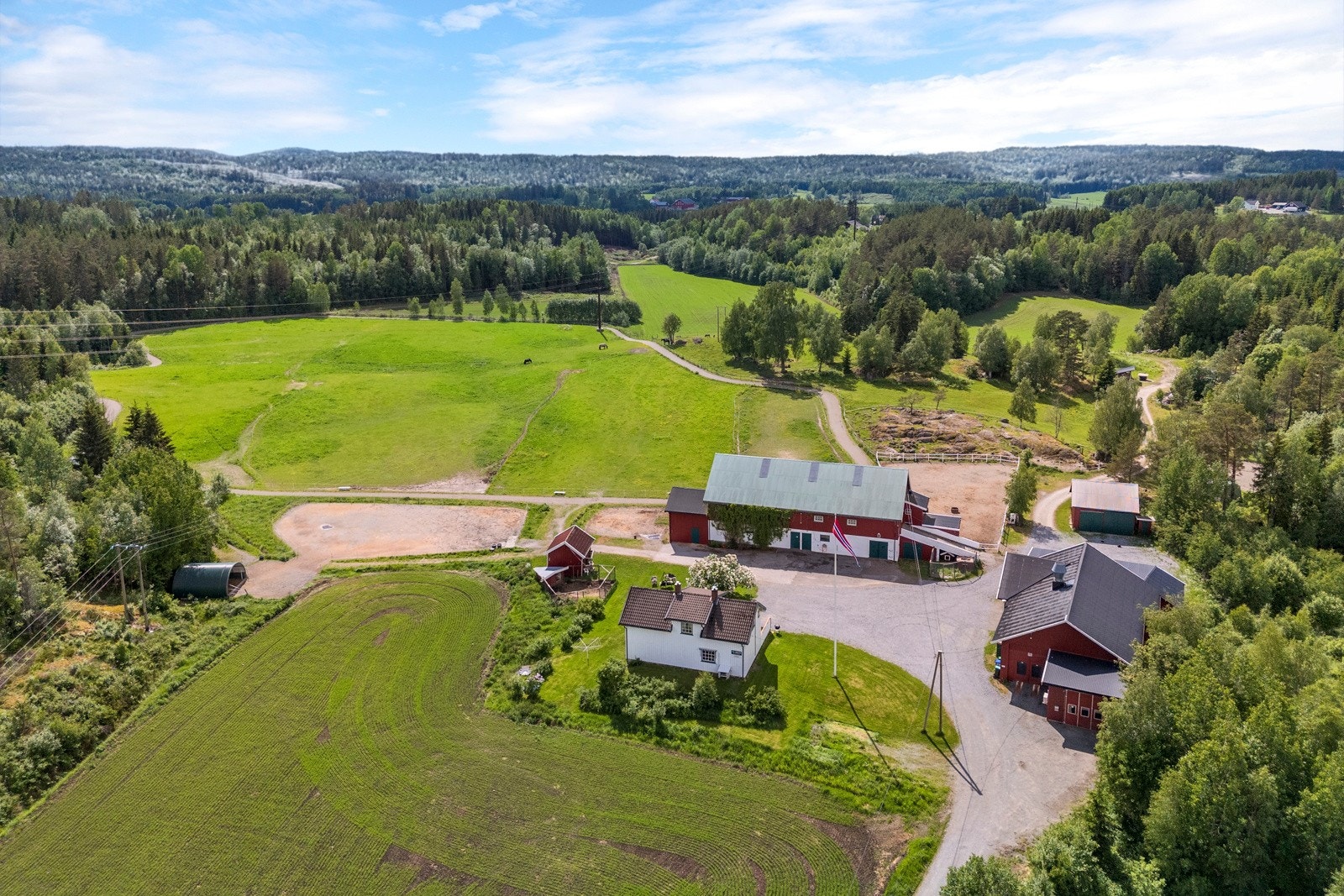 Nydelig tun bestående av stor, gruset gårdsplass og opparbeidet hage med prydbusker og beplantning Galleribilde