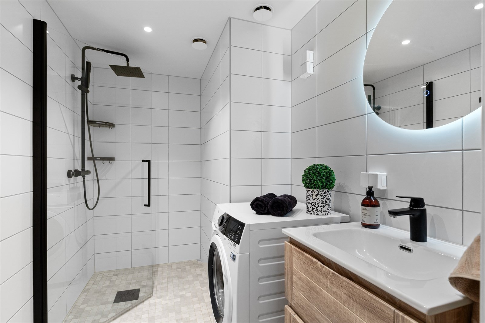 Pent og moderne bad med dusjhjørne rett på gulv med nedfliset dusjsone, regndusj og hånddusj. Galleribilde