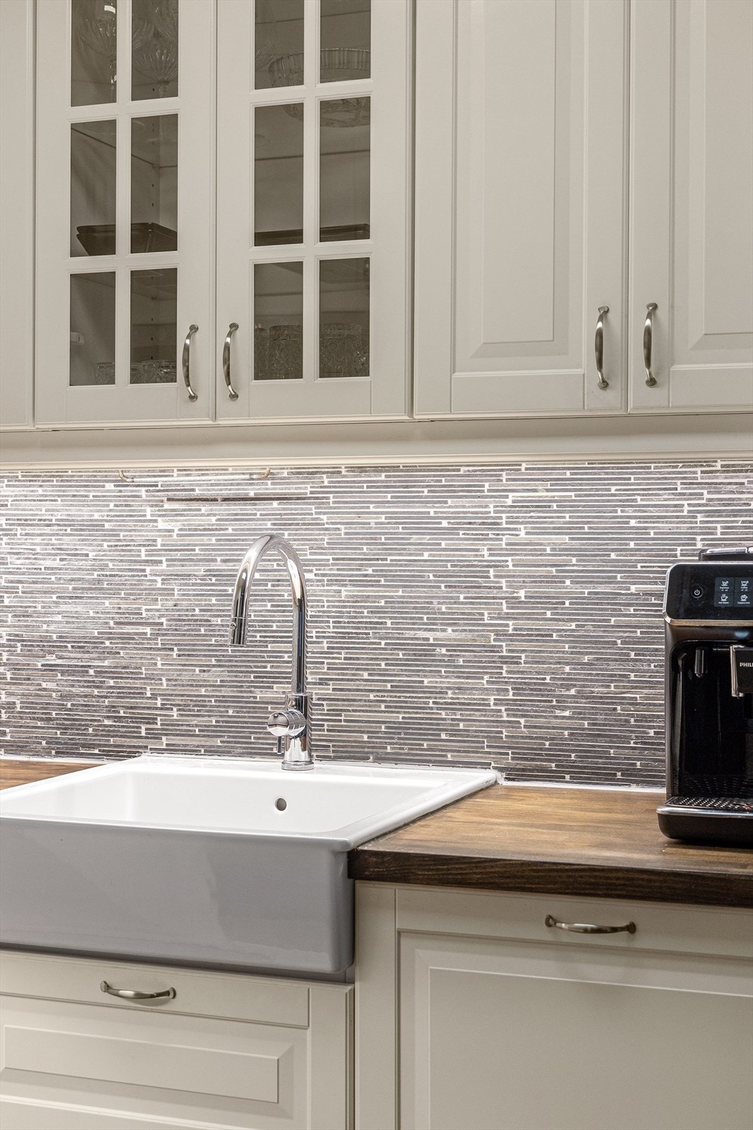 En stor oppvaskkum av porselen er nedfelt i mørk benkeplate, og over benken er det godt arbeidslys. Galleribilde