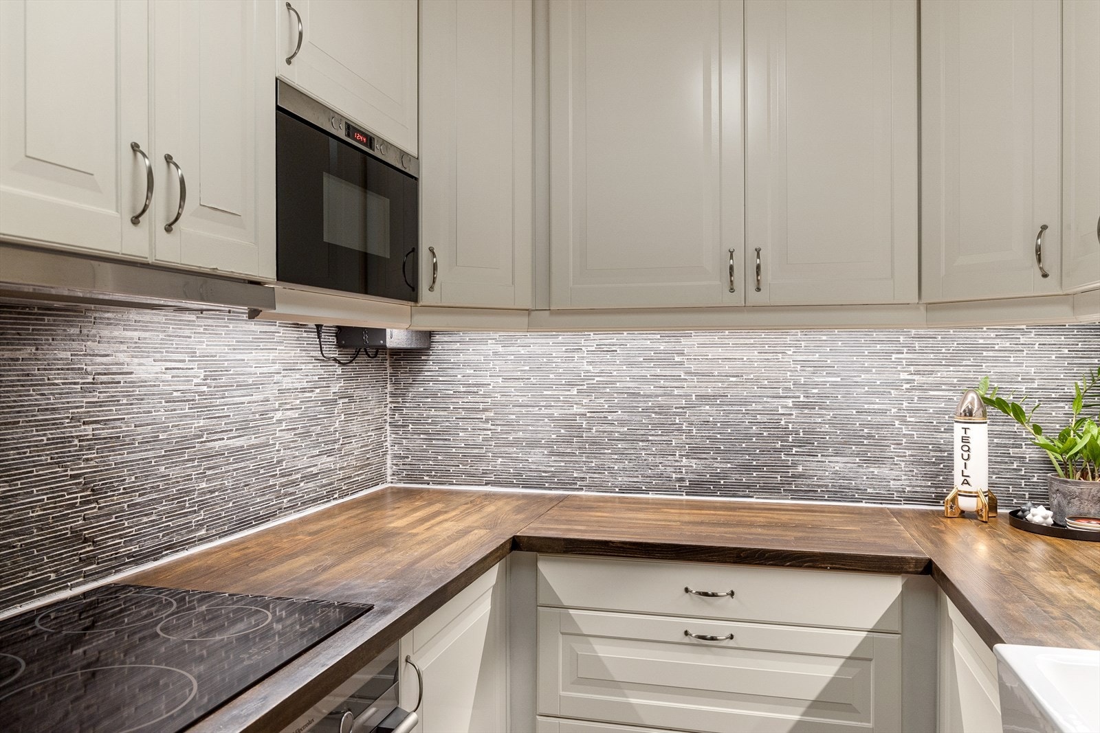 Innredningen har takhøye skap, kremhvite profilfronter og vitrineskap. Galleribilde