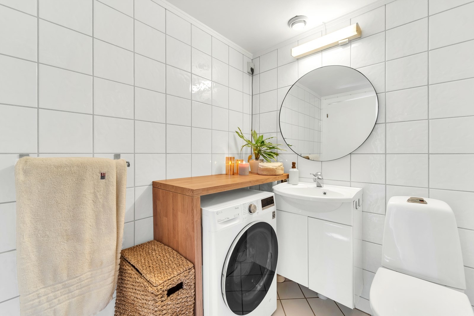 Baderomsinnredning med nedfelt servant på underskap med speil og belysning over. Installasjoner med dusjkabinett, toalett og opplegg for vaskemaskin. Galleribilde