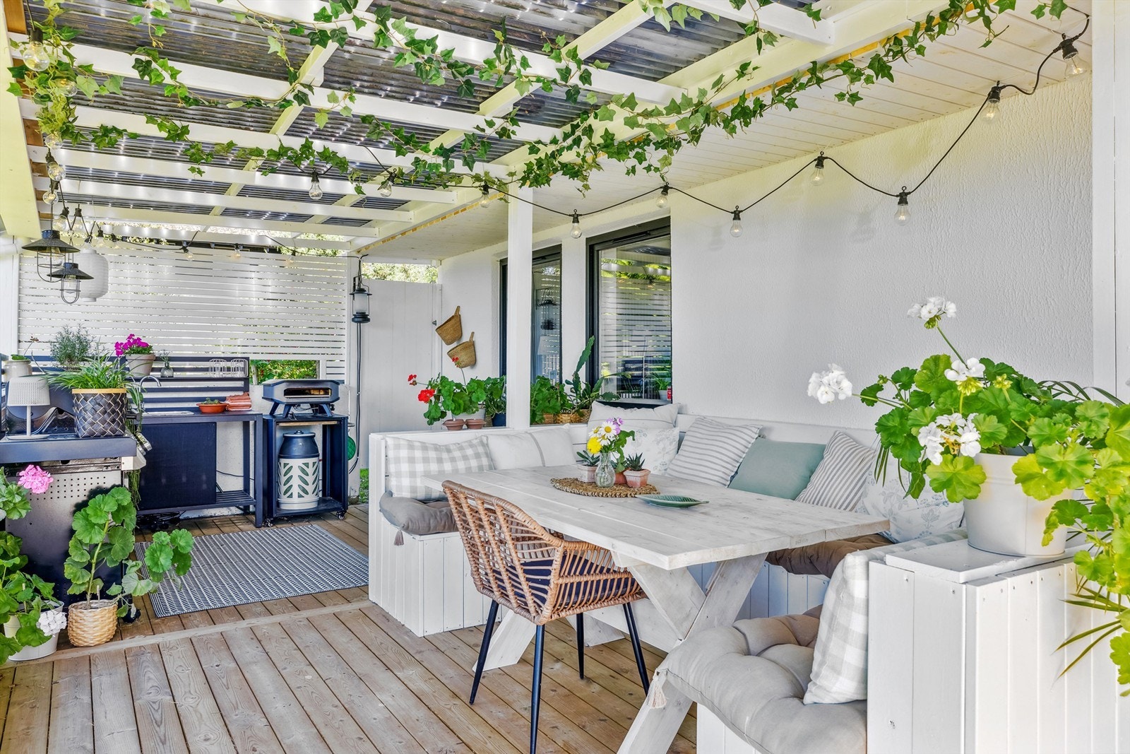 Under verandaen er en skjermet uteplass med plass til utekjøkken. Der er det også plassbygget sofa og bord. Denne plassen er nydelig for skygge på varme dager, men det er sol der om kveldene. Det er lunt og trivelig å sitte der alle årstider i le for vind Galleribilde