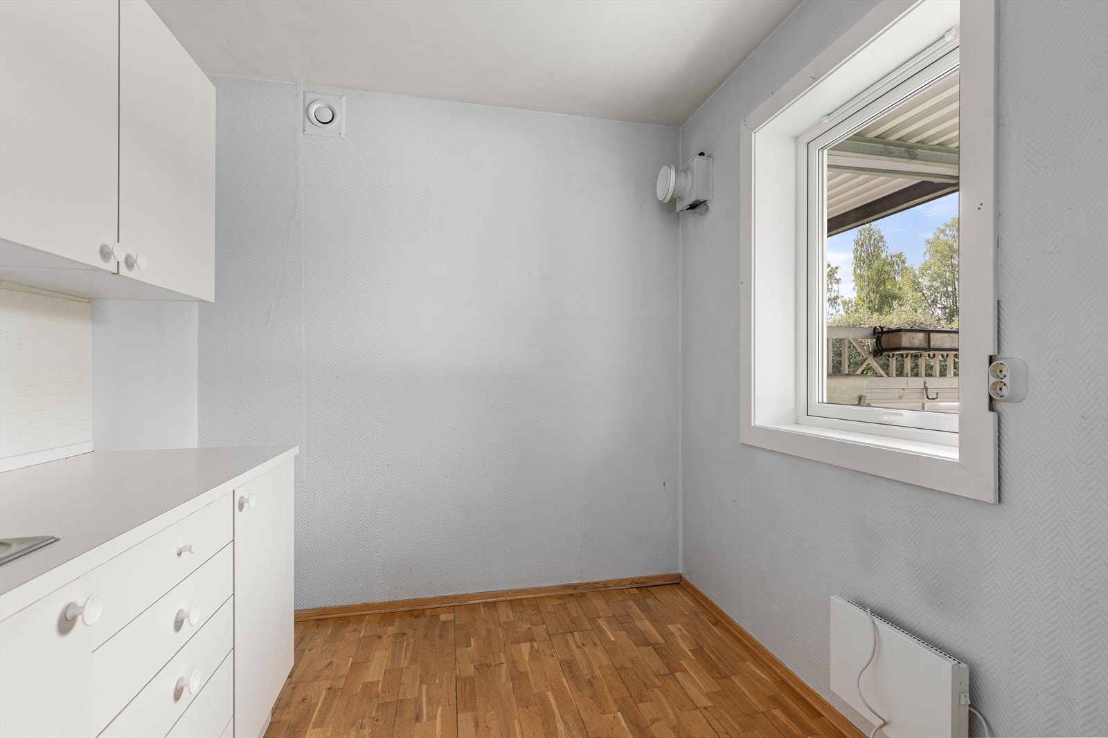 Kjøkken med innredning med hvite glatte fronter og plass til lite spisebord ved vindu Galleribilde