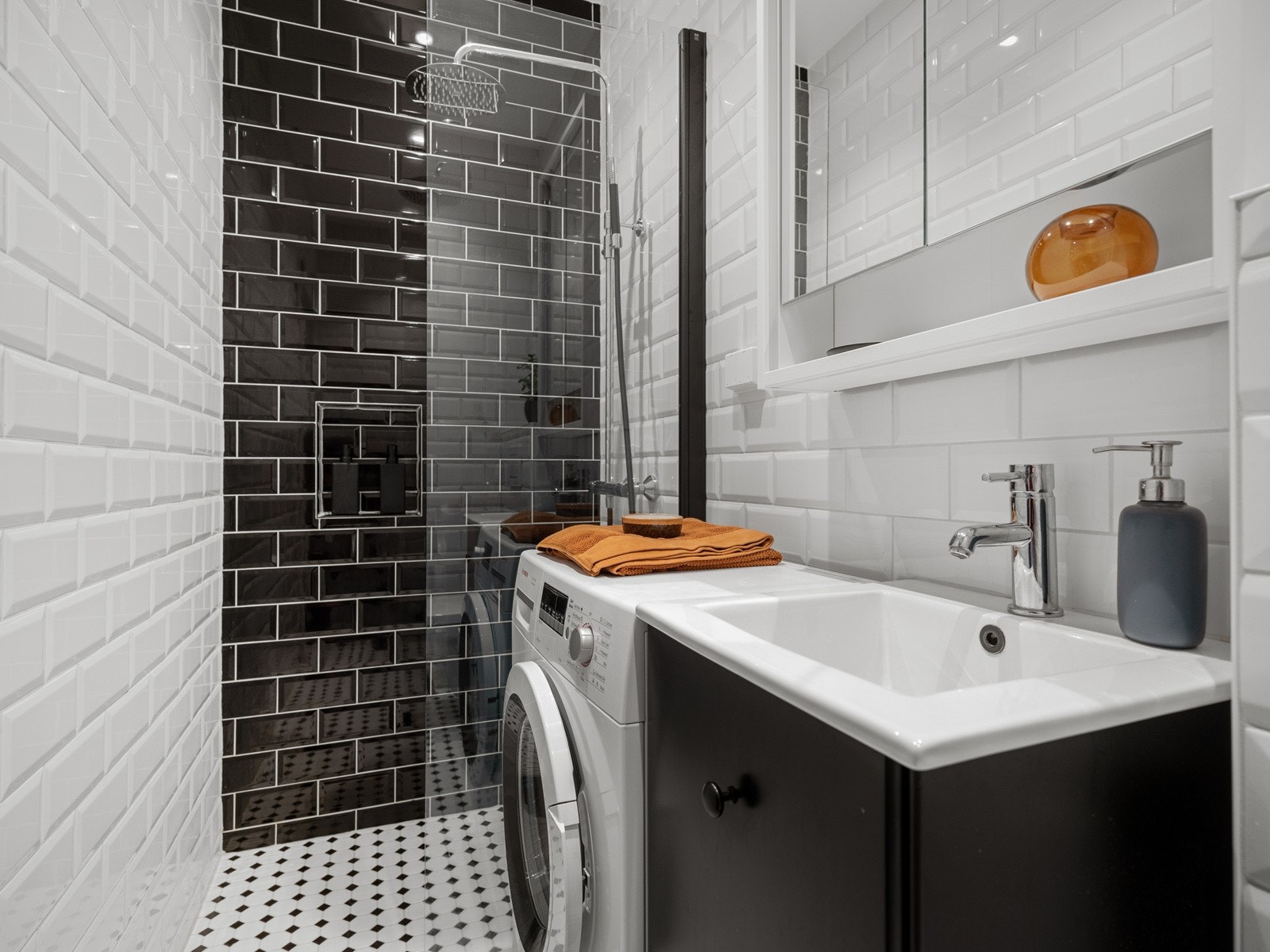 Baderommet inneholder servantskap, speilskap med stikkontakt, vegghengt toalett og dusj med veggmontert hånd- og regndusj. Galleribilde