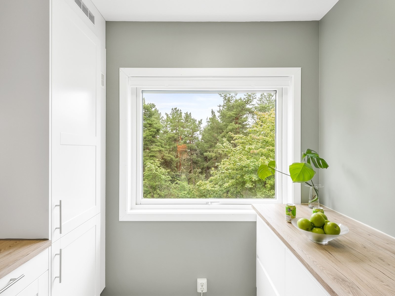 Kjøkken med stort vindu og utsikt over grøntområder. Galleribilde