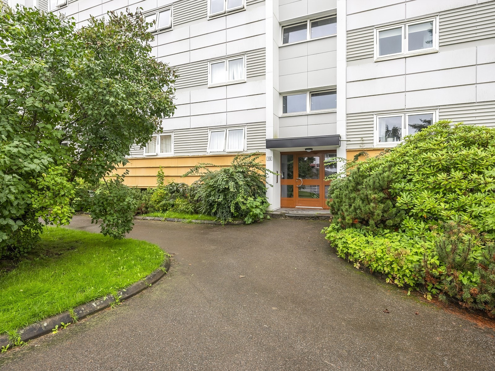 Inngangsparti til bygningen med velholdt hage. Galleribilde