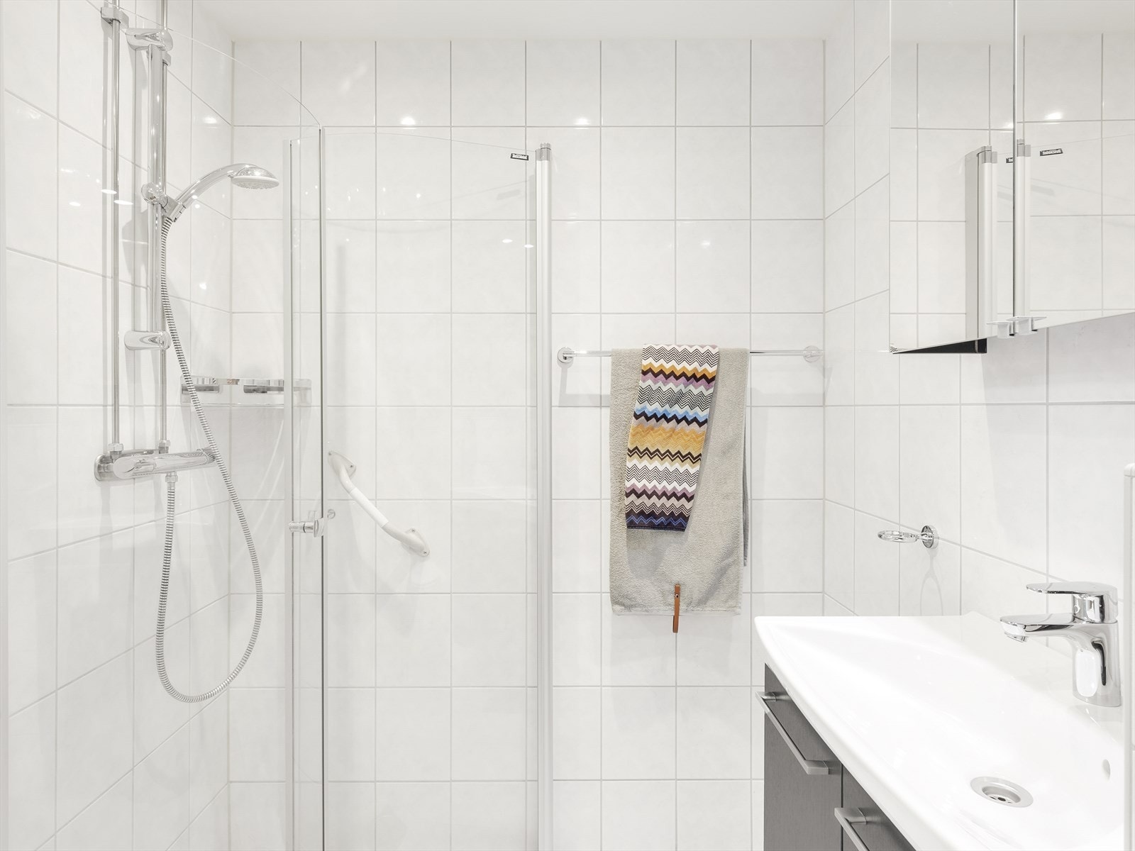 Lyst bad med dusjsone og stilrene fliser. Galleribilde