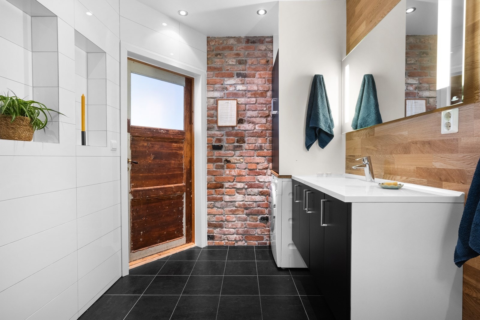 Høyskap med plass for vaskemaskin ved teglsteinsveggen og flere innfelte hyller/nisjer. Galleribilde