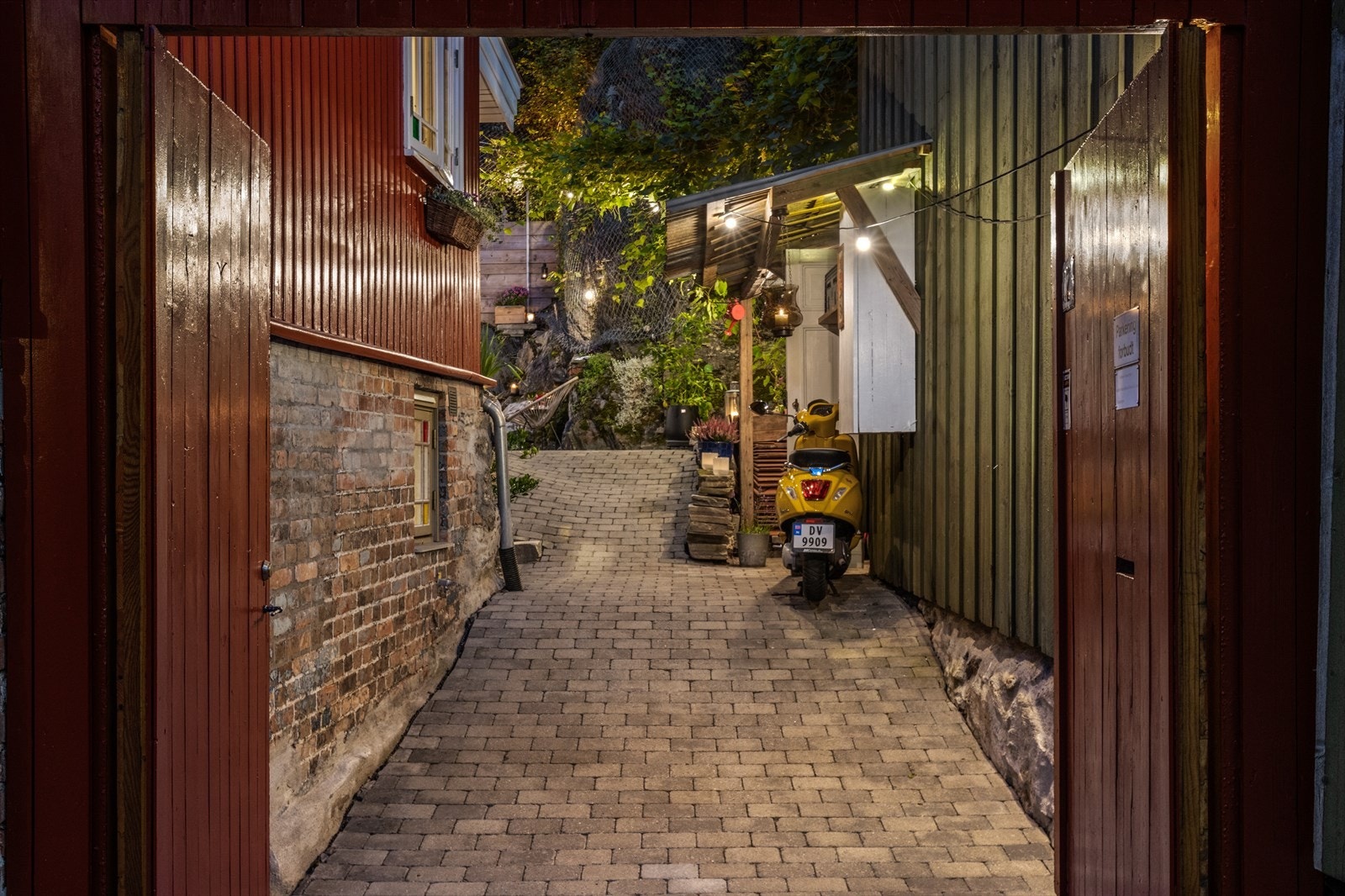 Den massive porten laget av gamle gulv fra huset åpner veien opp til en sjeldent vakker og stemningsfull bakgård. Galleribilde